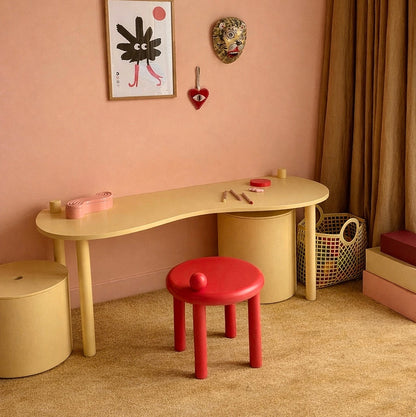 Playful and colourful kids' room with curvy desk, sculptural stool and aesthetically pleasing storage solution