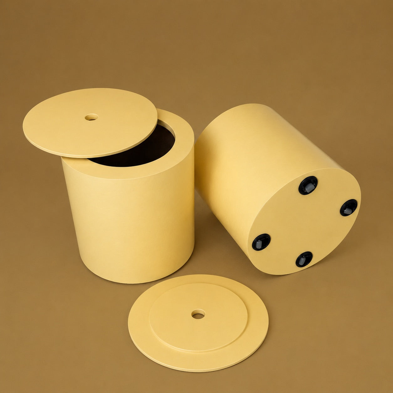 A pale yellow cylindrical container with a matching round lid, shown in two positions on a solid brown background: one standing upright with the lid off, and one lying on its side showing round black fasteners. A separate lid is placed in front.